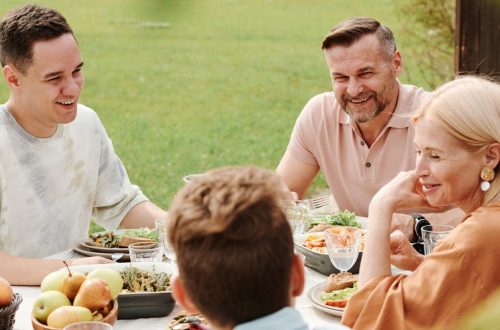 A cheerful family enjoying a meal together outdoors, sharing laughter and warmth.